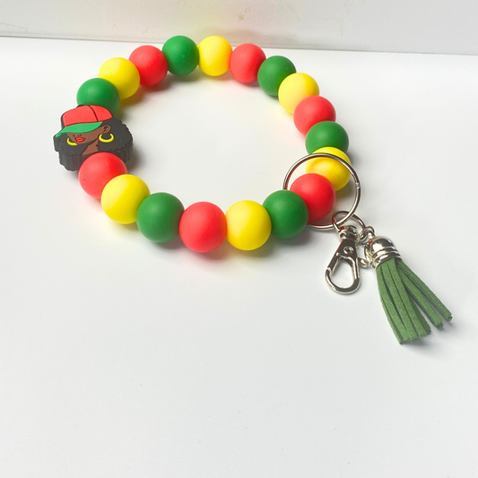 Colorful beaded keychain with a Jamaican flag-themed charm on a white background