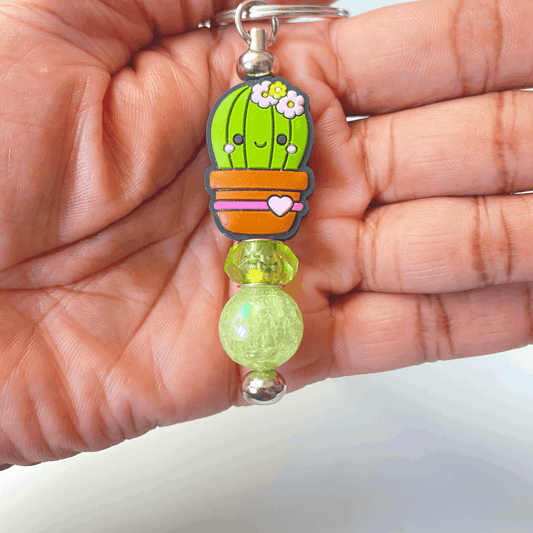 Keychain with a cute cactus design held in a hand against a plain background