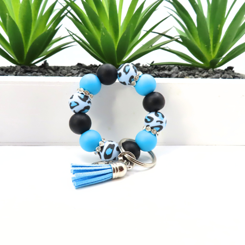 Beaded keychain with blue and black beads and tassel on a white background