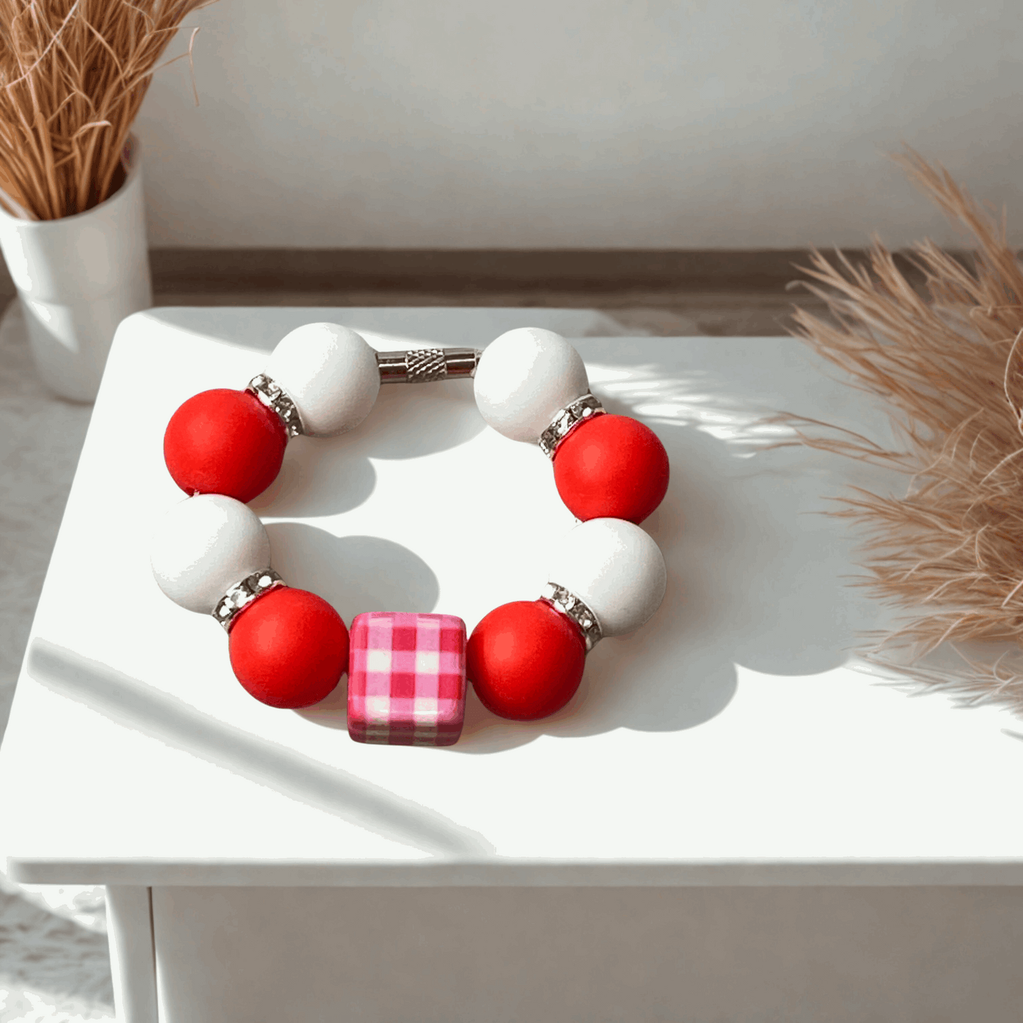 Bracelet with red and white beads on a white surface