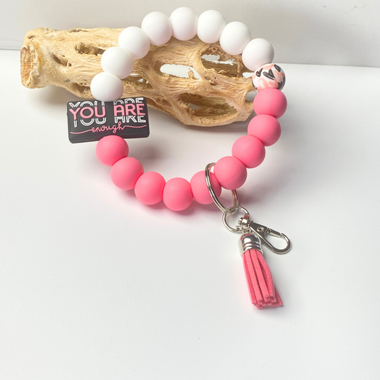 Pink beaded keychain with tassel on a white surface