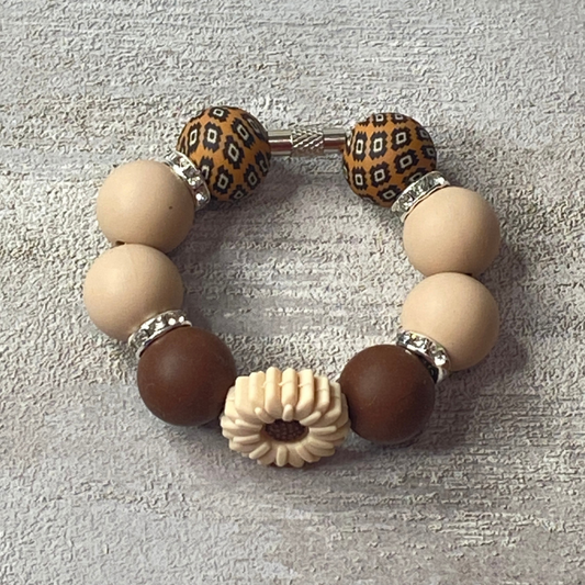 Bracelet with brown, beige, and patterned beads on a textured surface