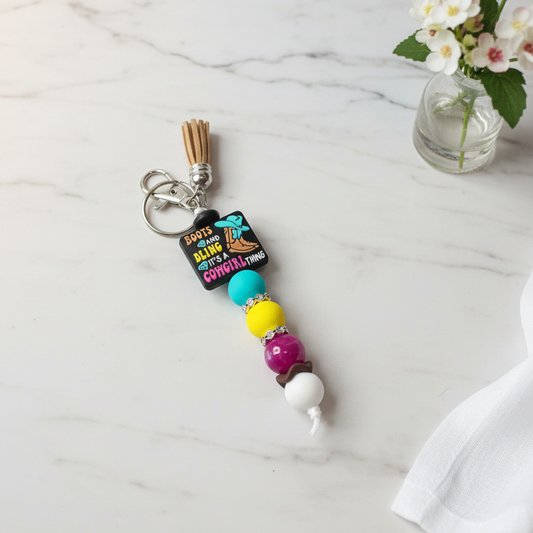 Colorful beaded keychain with a clip on a textured gray background