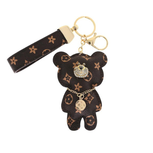 Brown teddy bear keychain with gold accents on a white background
