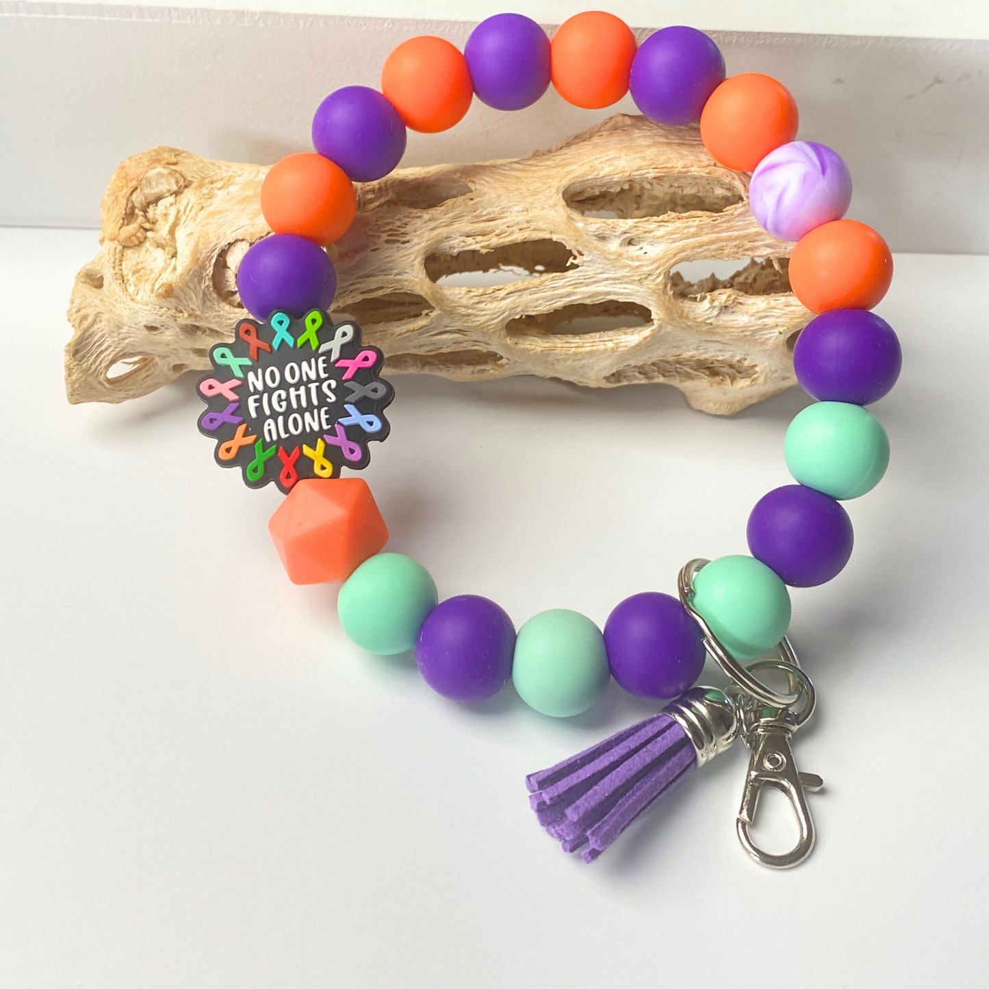 Colorful beaded bracelet with a keychain and motivational charm on a white background