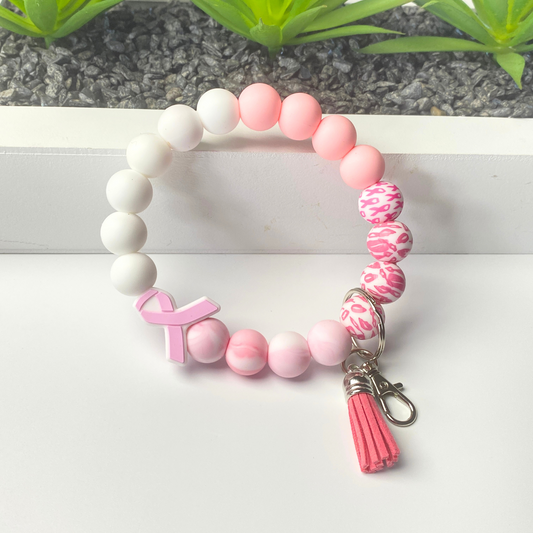 Bracelet with pink and white beads and a tassel on a white surface.