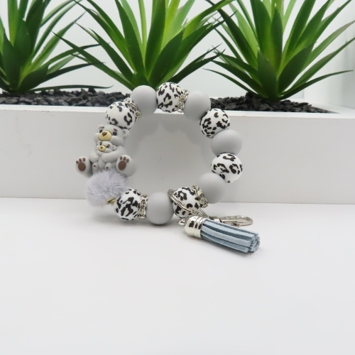 Bracelet with animal print beads and tassel on a white surface with plants in the background