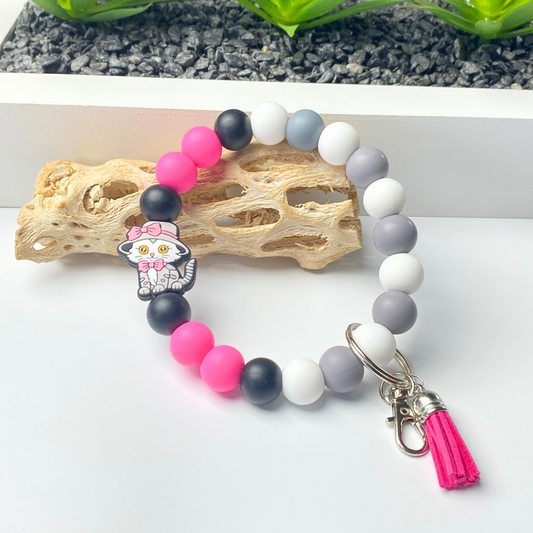 Beaded bracelet with colorful beads and a keychain charm on a white surface.