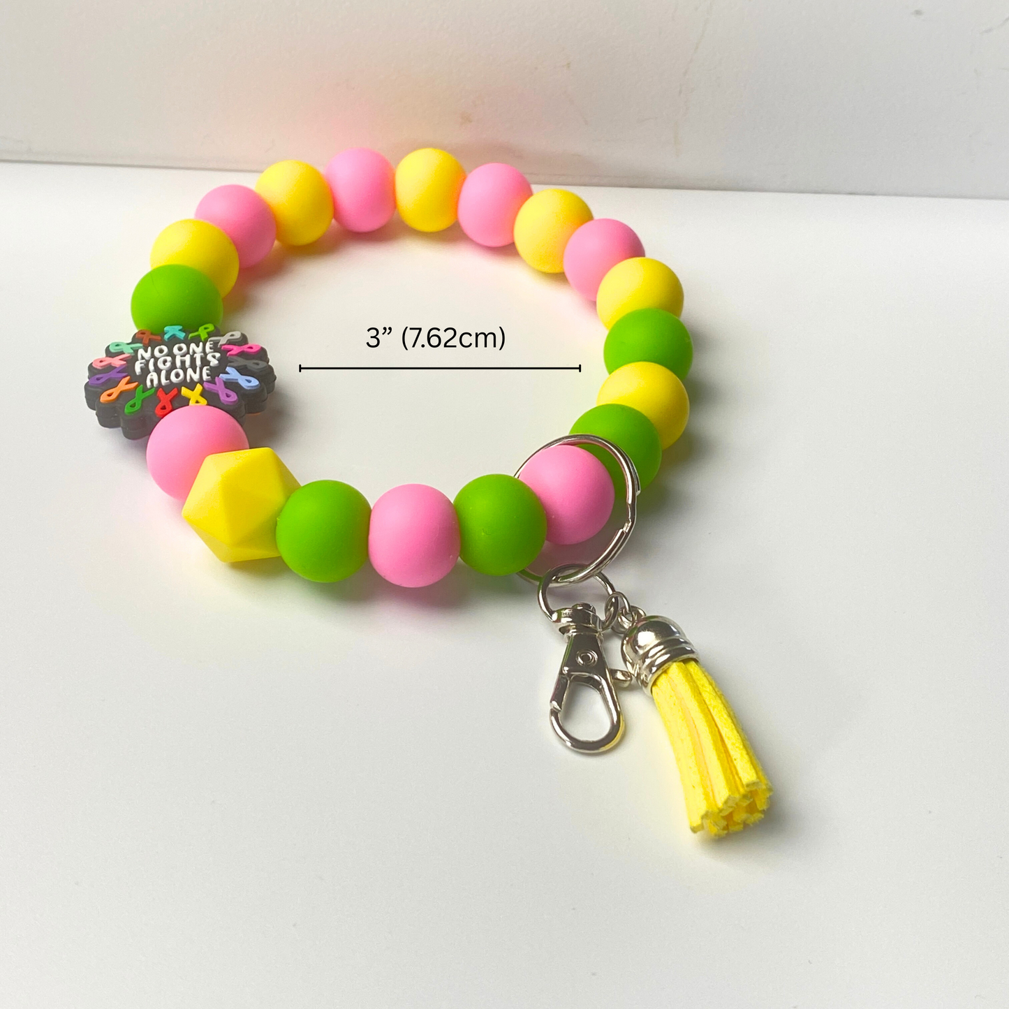 Colorful beaded bracelet with a tassel charm on a white background