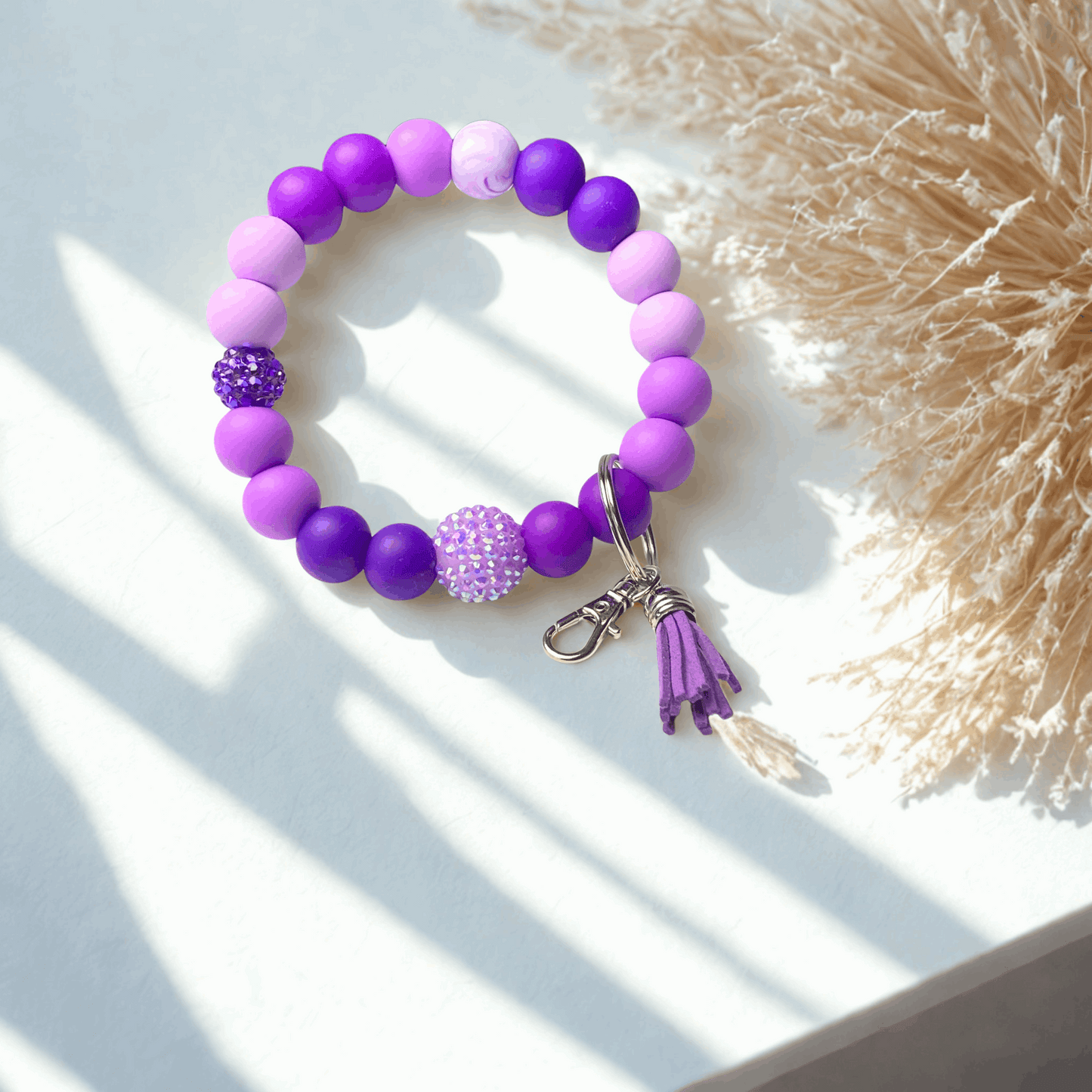 Purple beaded bracelet with a tassel on a light surface