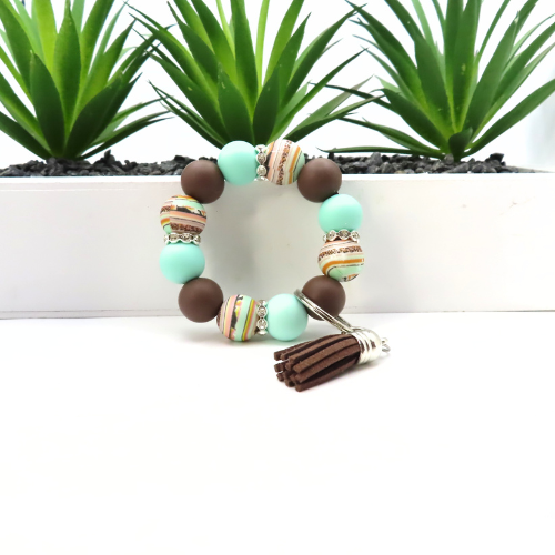 Beaded bracelet with tassel on a white background with green plants in the background