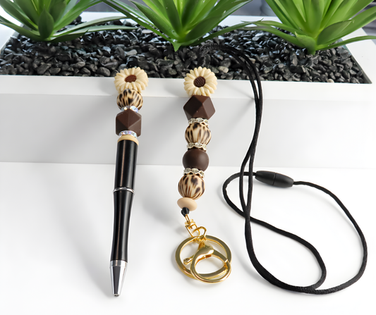 Pen with decorative beads and a keychain on a white surface with plants in the background