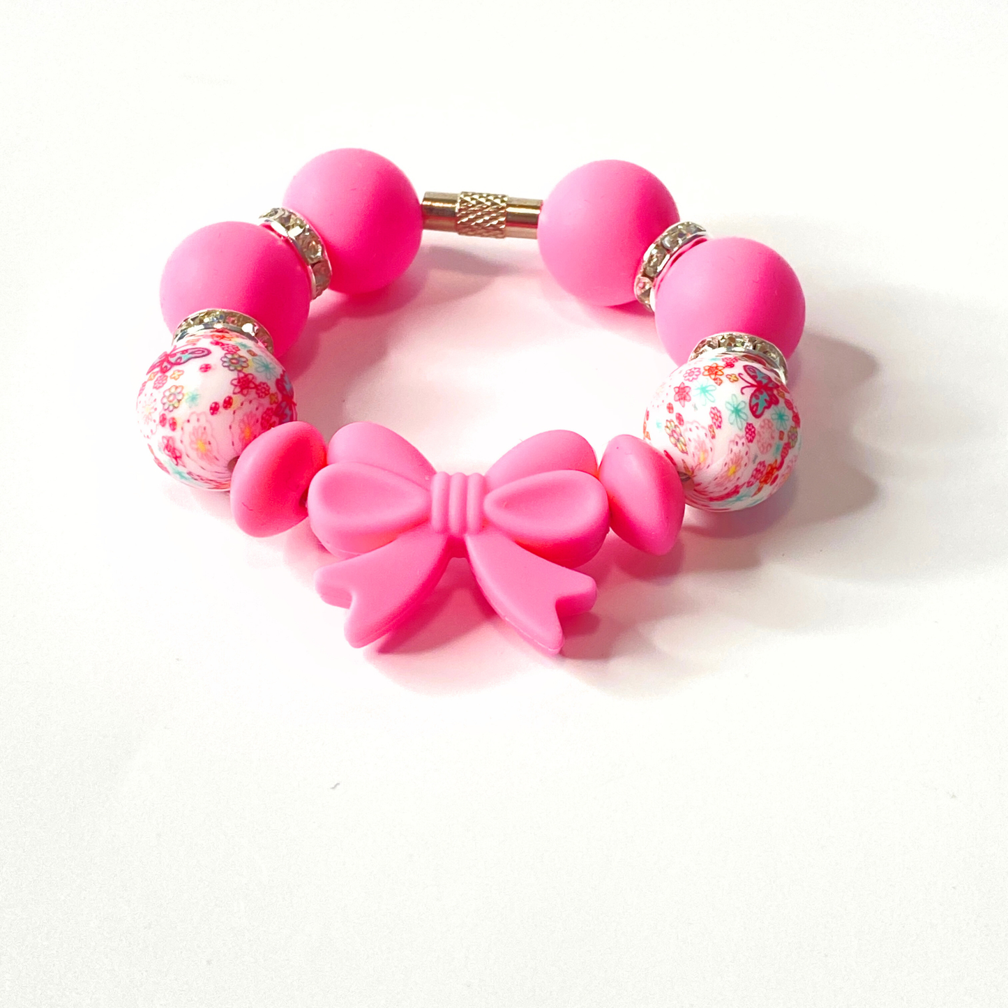 Pink bracelet with floral beads and a bow on a white background
