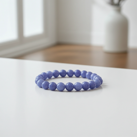 Purple beaded bracelet on a white surface with a blurred background