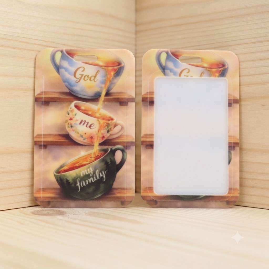 Two rectangular phone cases shown on a light wood surface. One case has a printed design of three teacups with the words 'God', 'me', and 'my family' in gold script, and the other case is blank with a white center and matching printed border.
