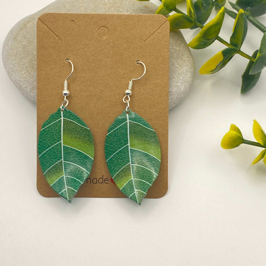 Leaf-shaped earrings on a brown card with a natural background