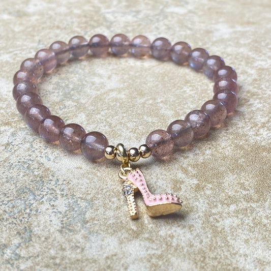 Beaded bracelet with a high heel charm on a textured surface