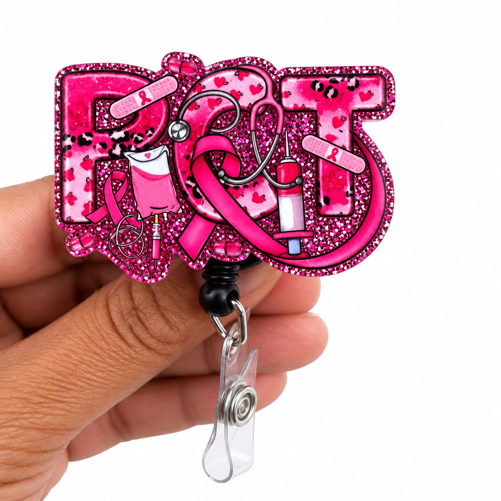 A hand holding a pink glitter acrylic badge reel or ID holder with the word 'ROX' in stylized letters, decorated with pink ribbons, hearts, and lipstick bullets, on a plain white background.
