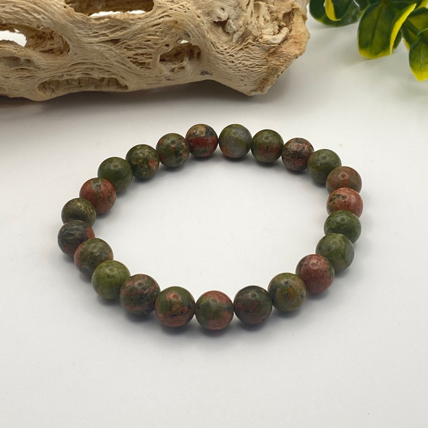 Beaded bracelet with green and red stones on a white surface
