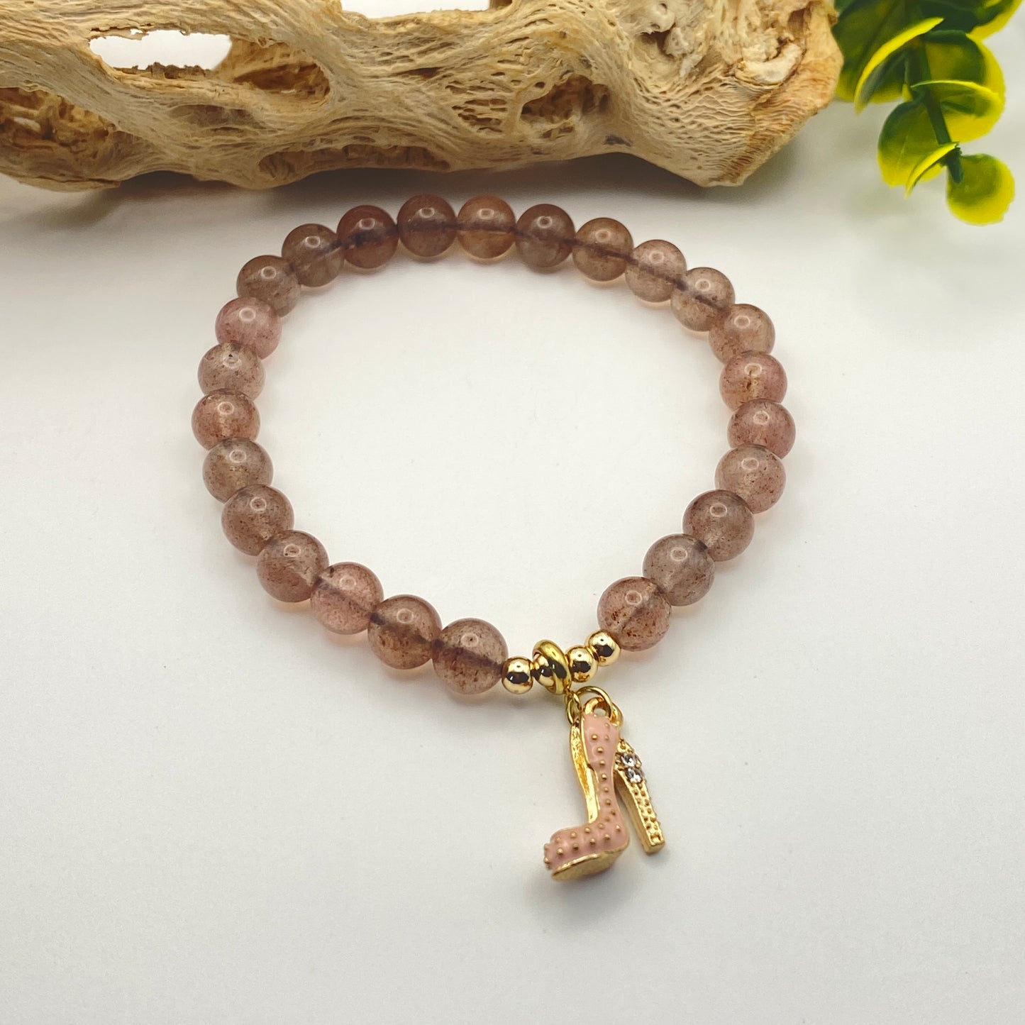 Beaded bracelet with a high heel charm on a light background