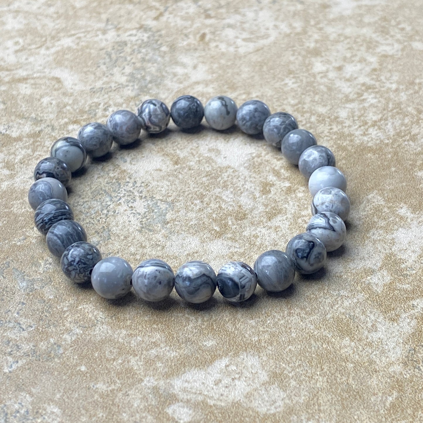 Gray beaded bracelet on a textured beige surface