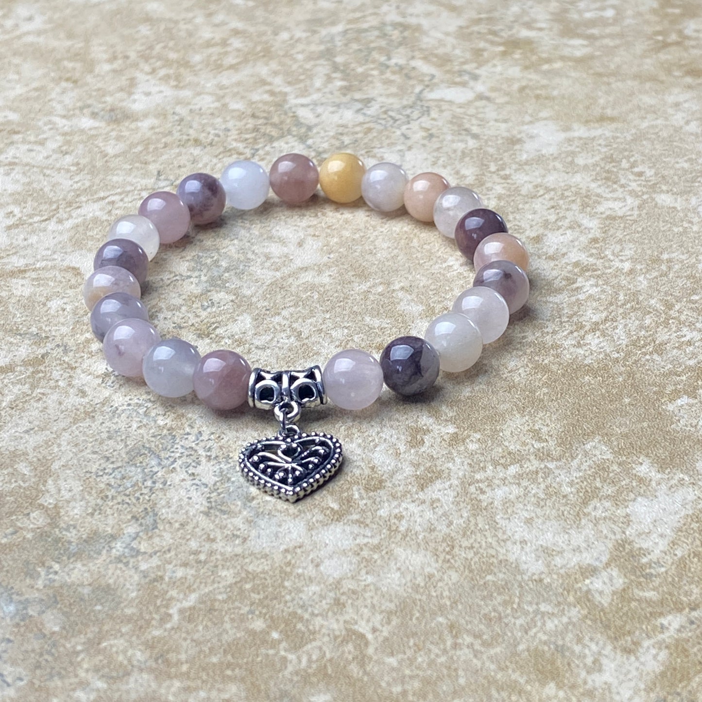 Beaded bracelet with a heart charm on a textured surface