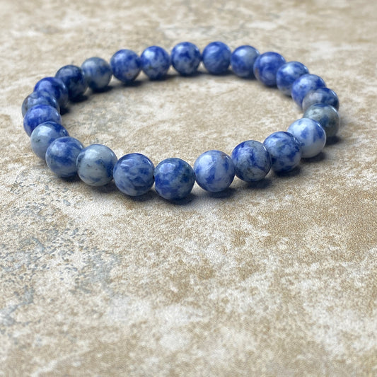 Blue beaded bracelet on a textured beige surface