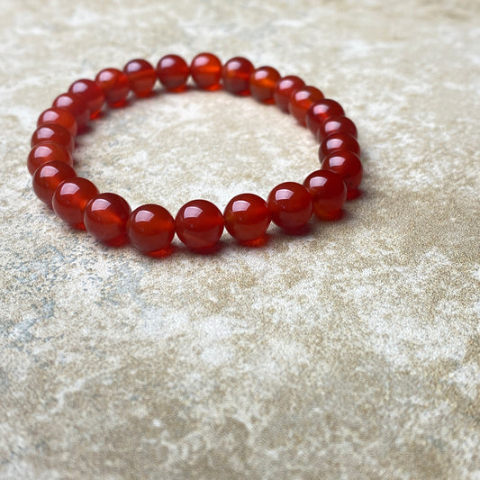 Red beaded bracelet on a textured beige surface