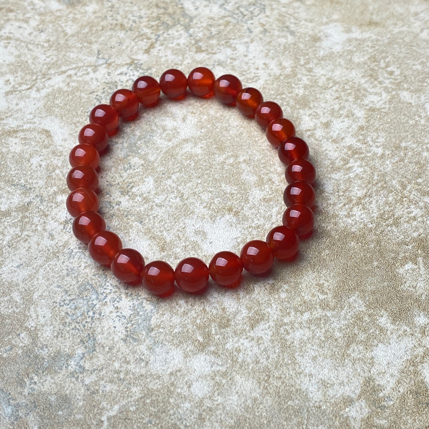 Red beaded bracelet on a textured beige surface