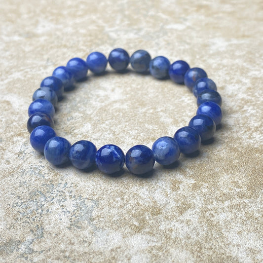 Blue beaded bracelet on a textured beige surface