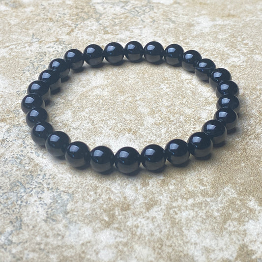 Black beaded bracelet on a textured beige surface