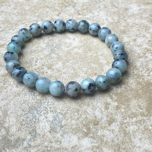 Beaded bracelet with blue and gray beads on a textured surface