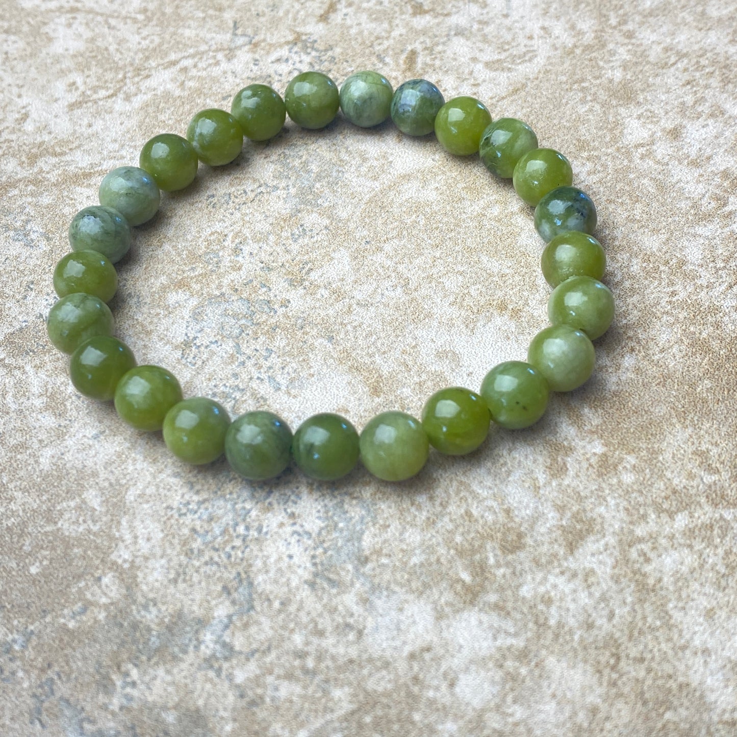 Green beaded bracelet on a textured beige surface