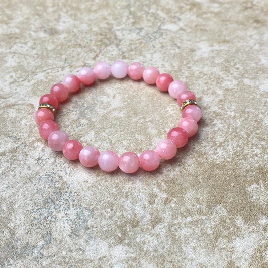 Pink beaded bracelet on a textured beige surface