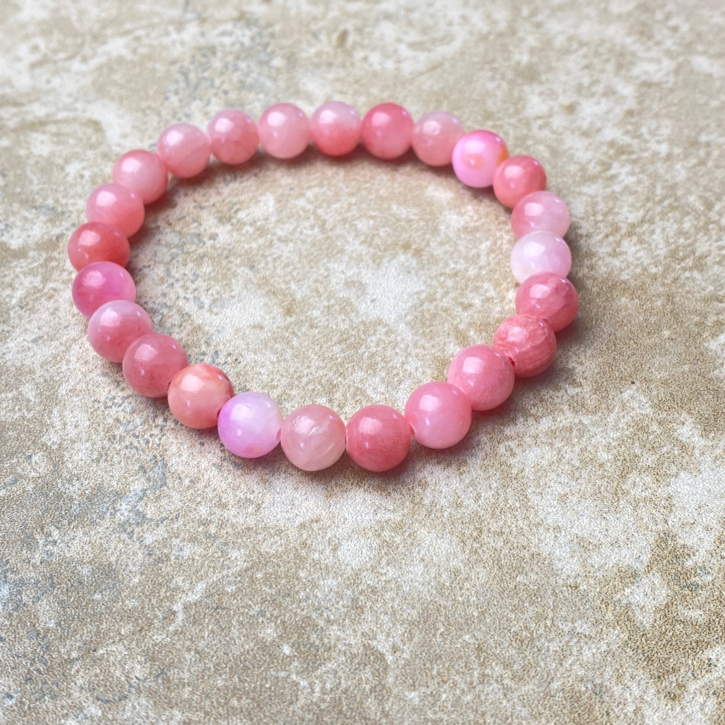 Pink beaded bracelet on a textured surface