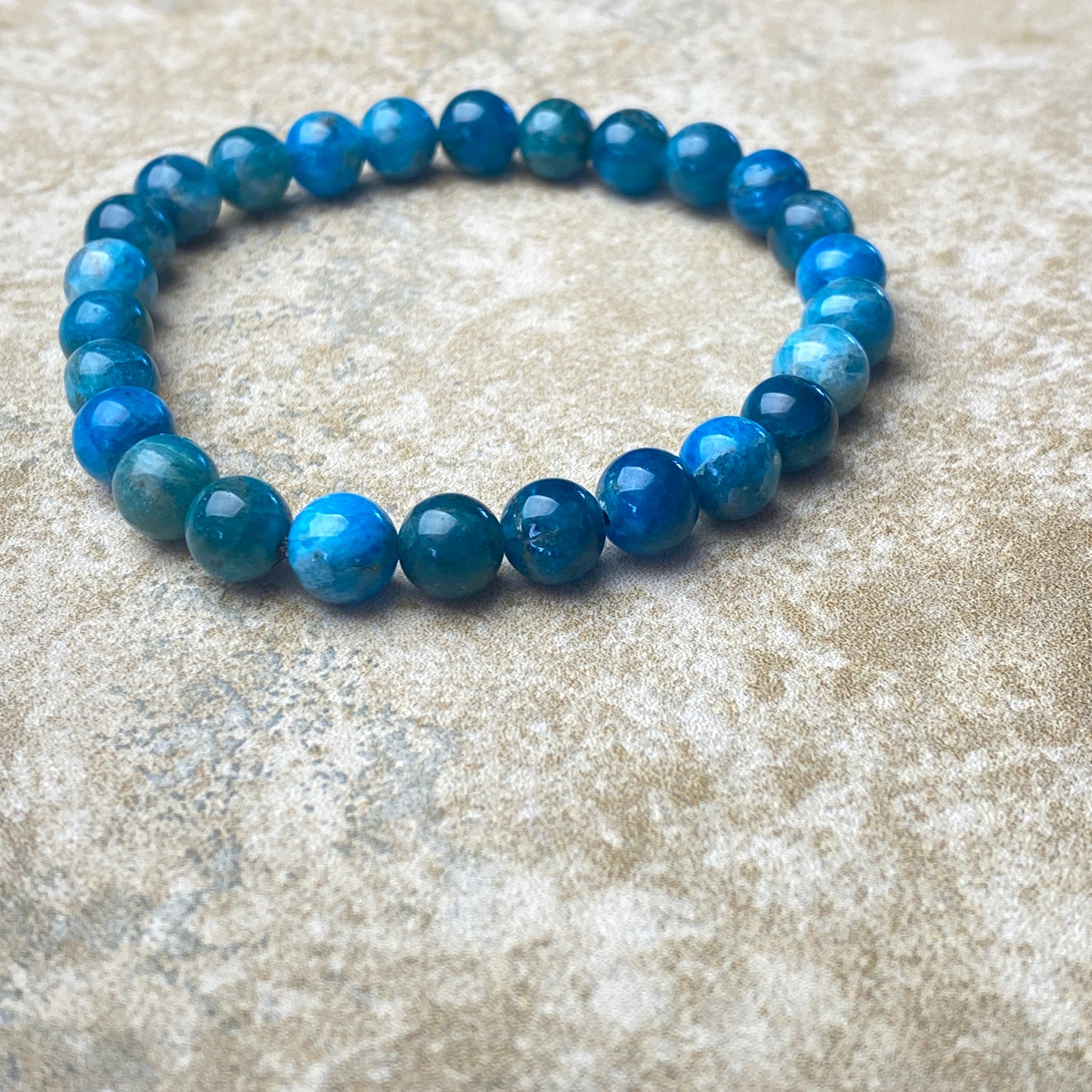 Blue beaded bracelet on a textured beige surface
