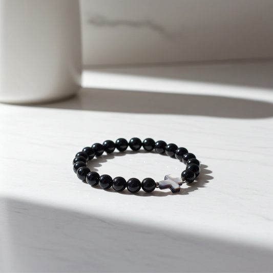 Black beaded bracelet with a star charm on a white surface