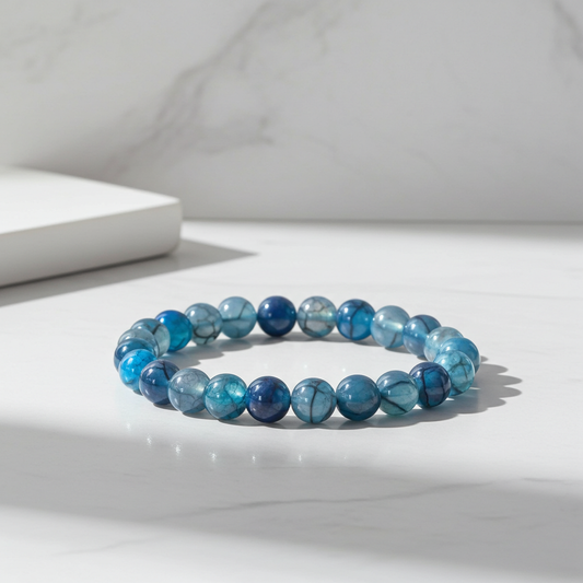 Blue beaded bracelet on a white surface with a neutral background