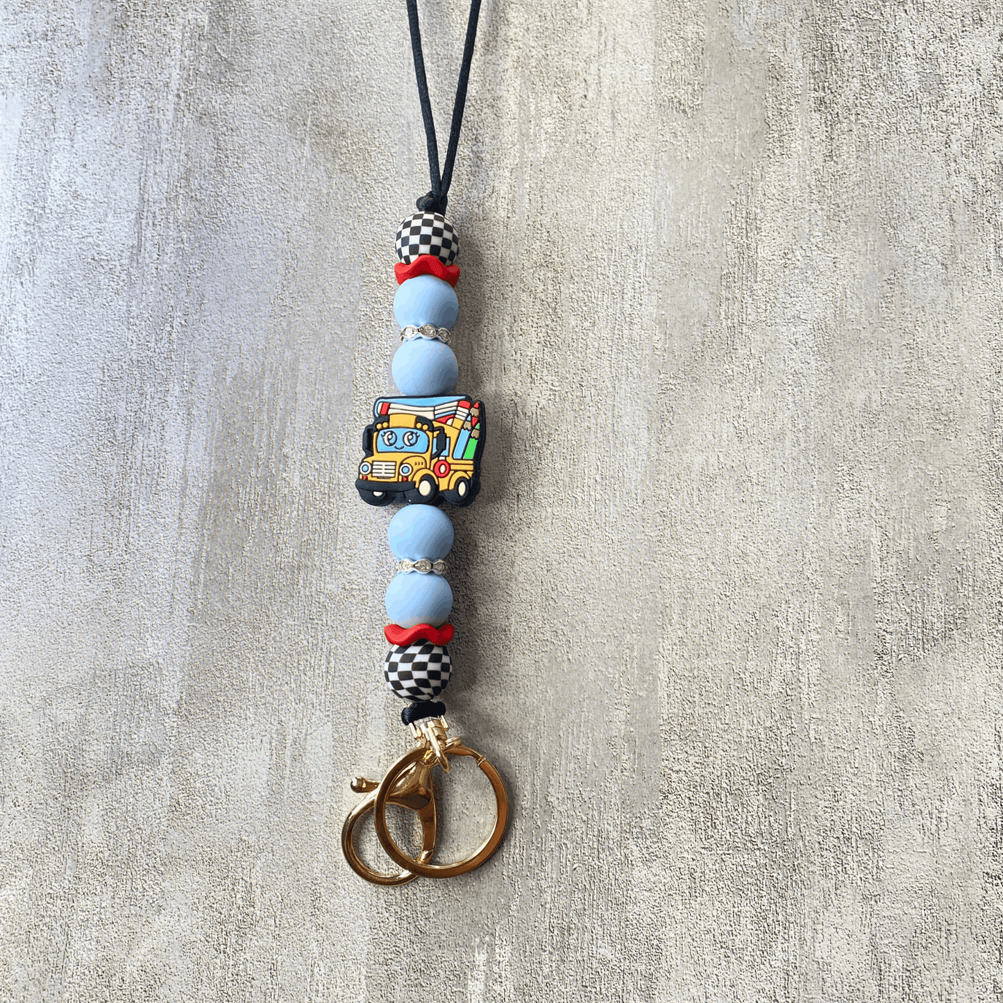 Beaded keychain with a colorful bus charm on a textured surface