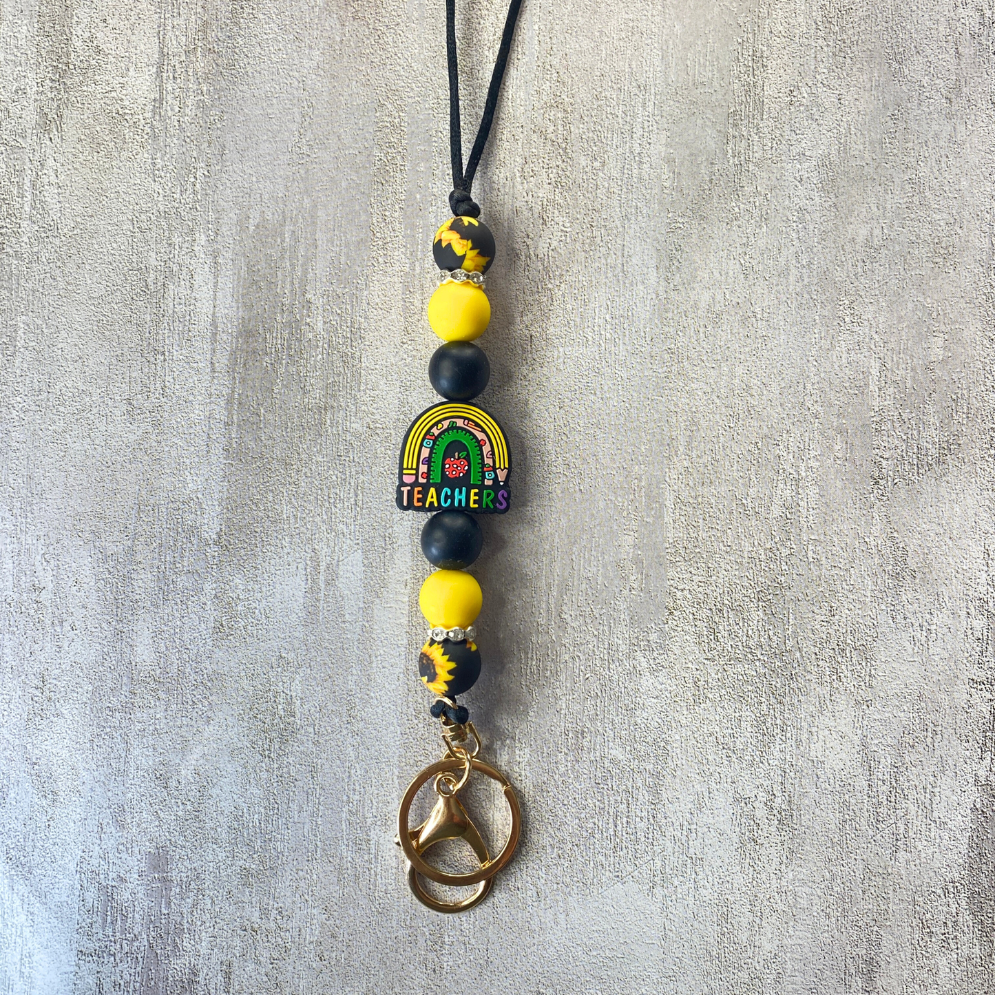 Beaded keychain with rainbow and 'Teacher' charm on a gray background