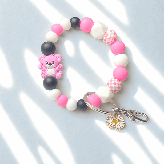 Colorful beaded bracelet with a teddy bear charm and keychain on a light background