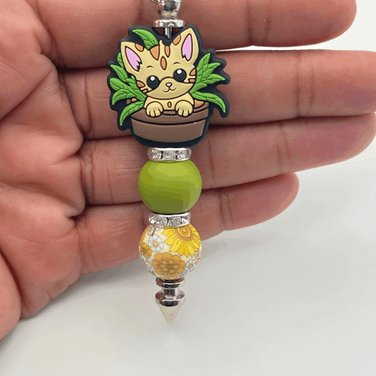 Keychain with a cat design held in a hand on a white background