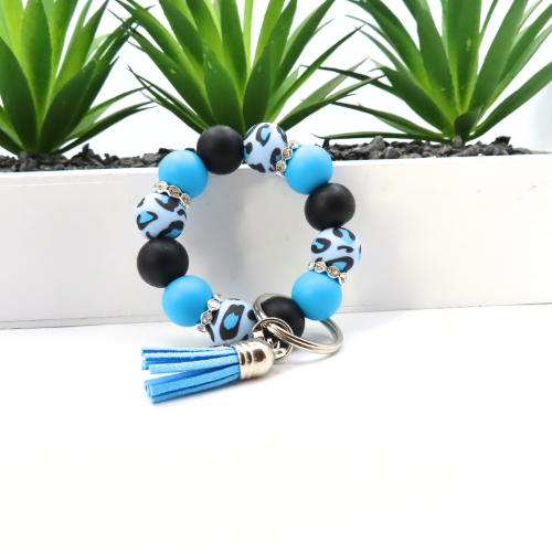 Beaded keychain with tassel on a white surface with green plants in the background