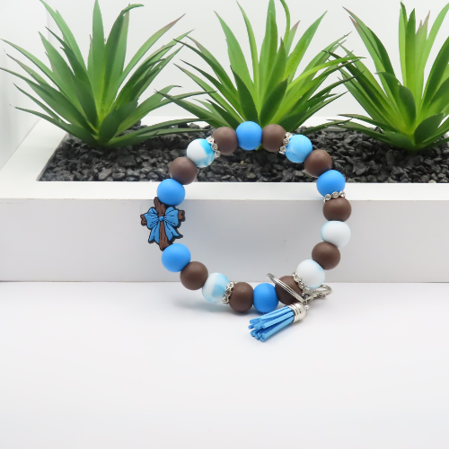 Beaded bracelet with blue, brown, and white beads on a white surface with plants in the background