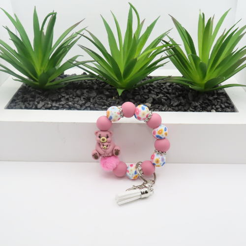 Pink teddy bear keychain with colorful beads on a white background