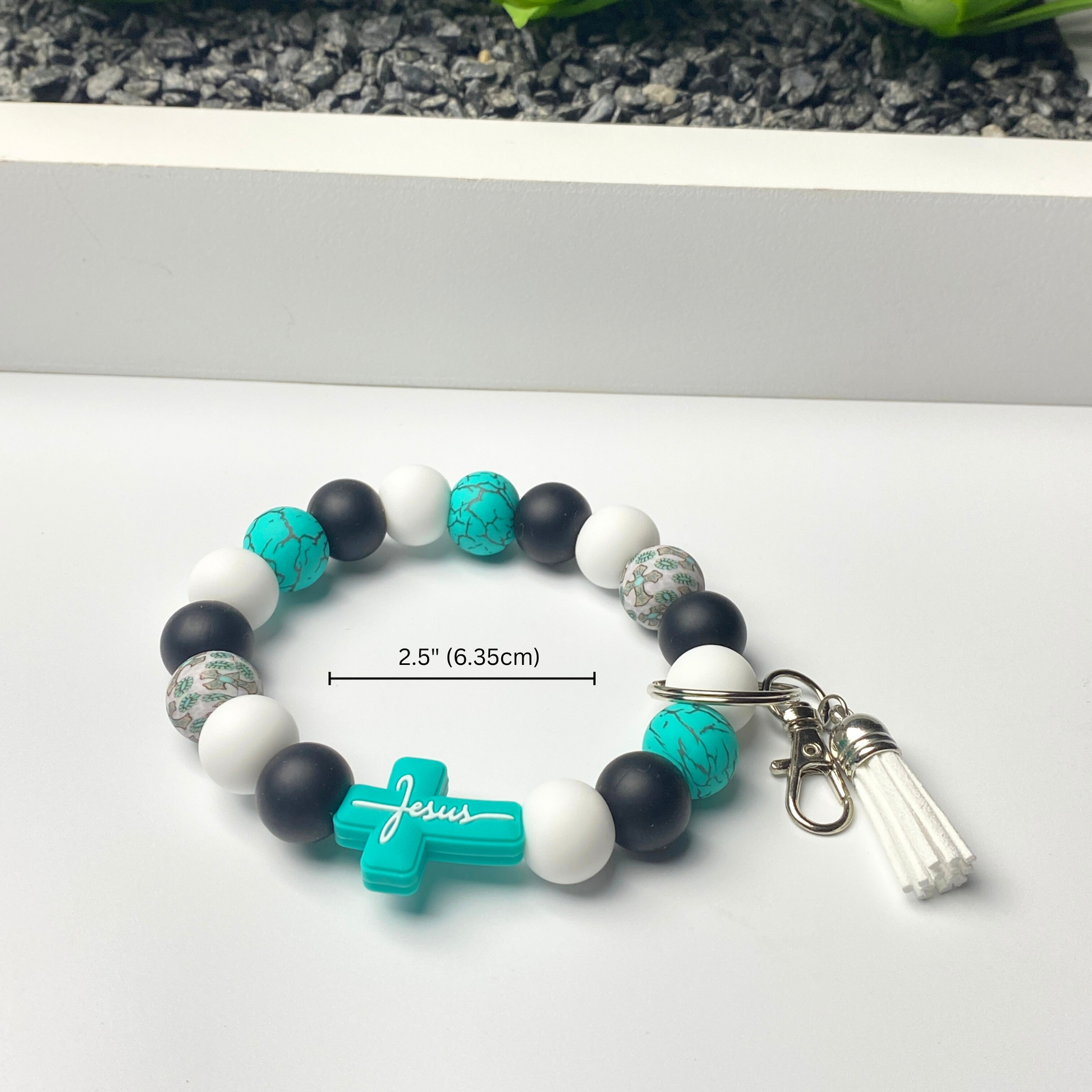 Bracelet with turquoise 'Jesus' cross charm on a white surface