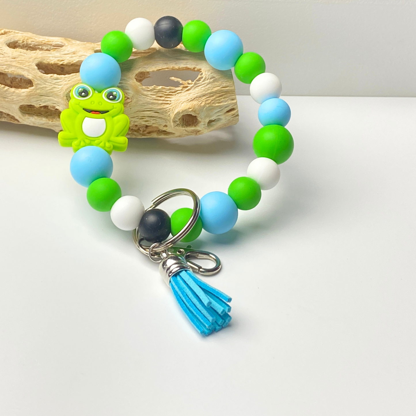 Colorful beaded bracelet with a frog charm and tassel on a light background