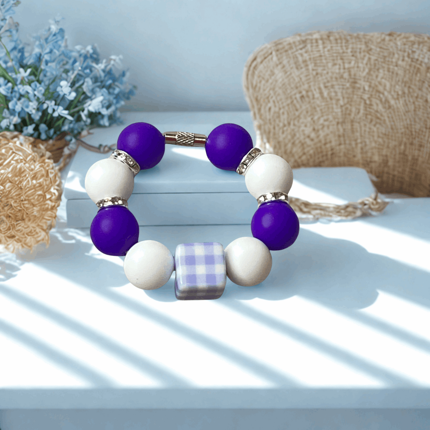 Bracelet with purple and white beads on a light surface with decorative elements.