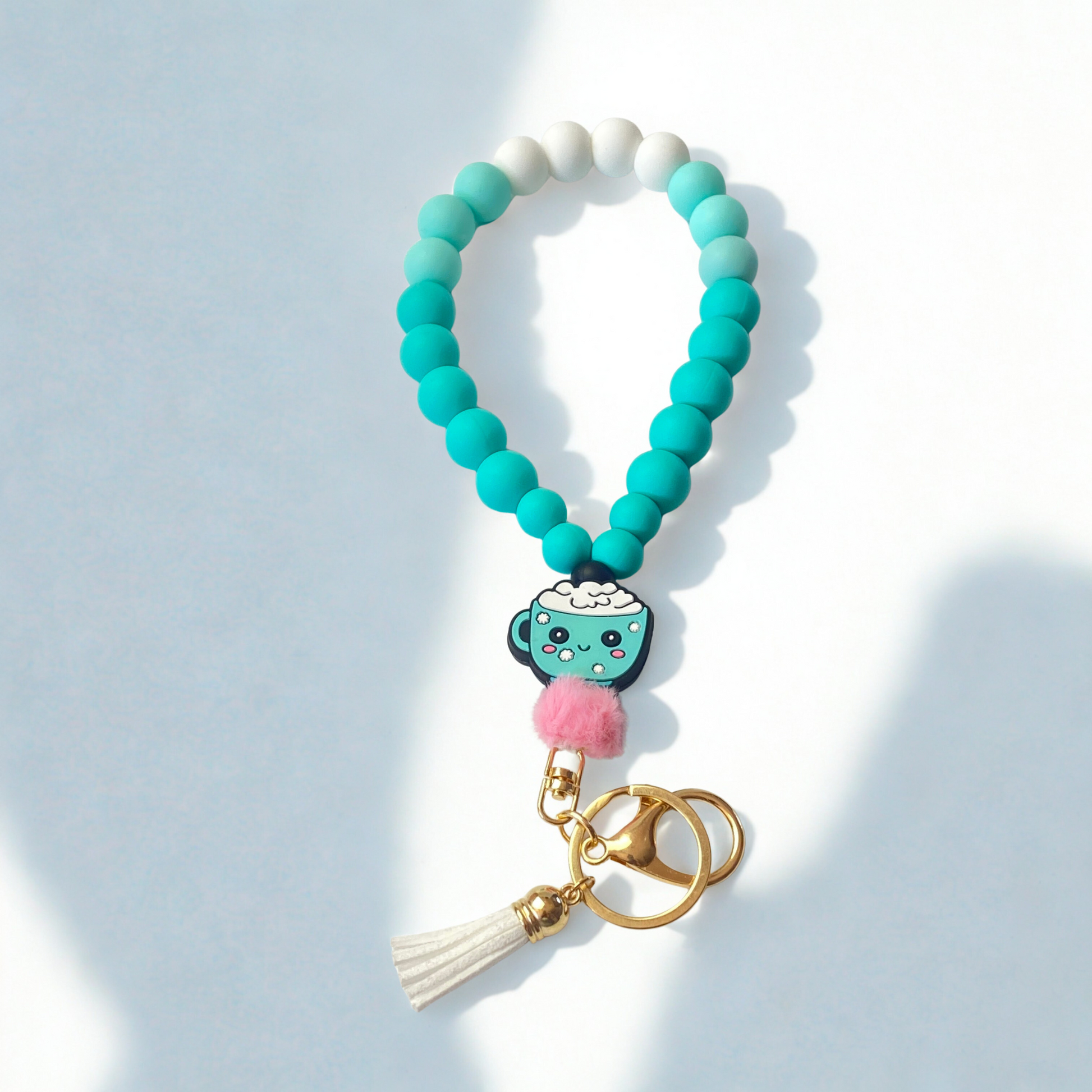 Teal beaded keychain with a coffee cup charm on a light blue background