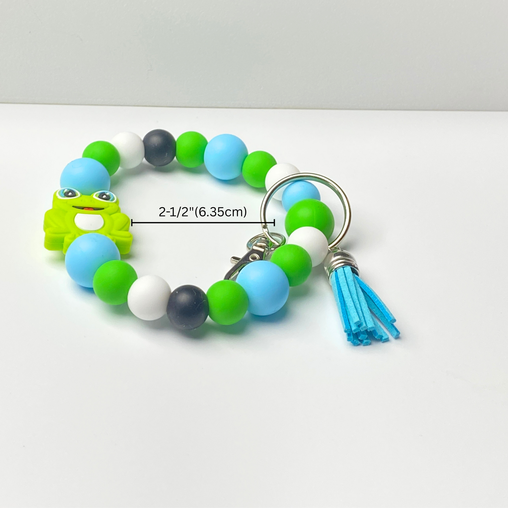 Beaded bracelet with a frog charm and tassel on a white background